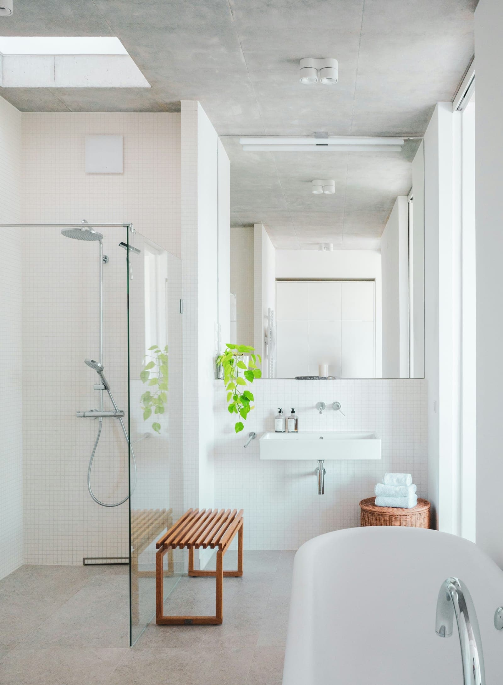 A bright, spotless tiled bathroom with a glass shower screen.