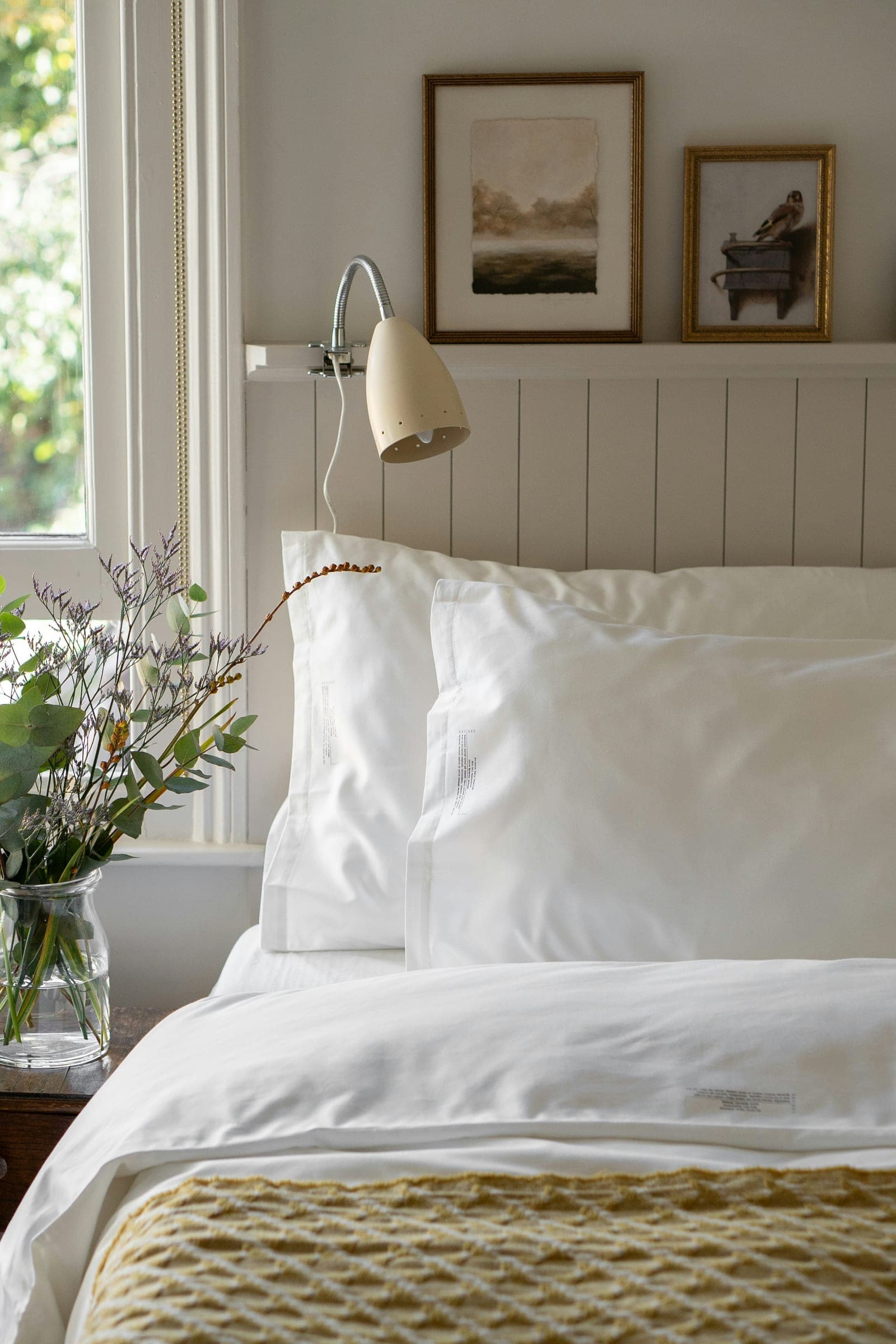 A freshly made bed with crisp white linens beside a window.